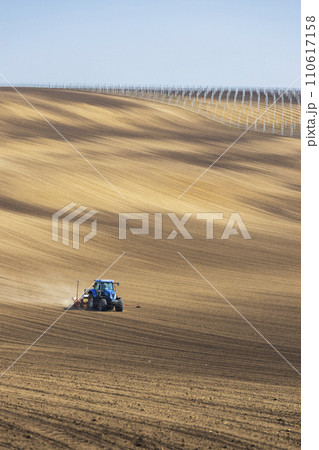 Tractor with seed drill in early spring landscape Tractor with seed drill in early spring landscape 110617158