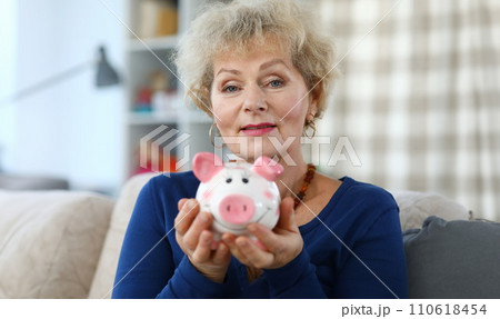 Portrait of woman with pink piggy bank in her hands 110618454