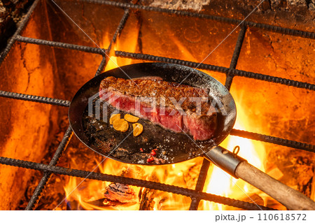 ワイルドに焼くステーキ　Grill a steak over an outdoor 110618572