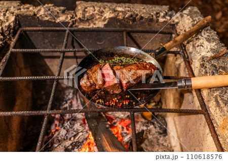 ワイルドに焼くステーキ　Grill a steak over an outdoor 110618576
