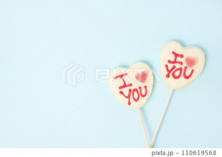 two Valentine's day heart shape candies with white chocolate on pastel blue paper background. Love Concept 110619568