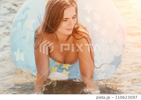 Woman summer sea. Happy woman swimming with inflatable donut on the beach in summer sunny day, surrounded by volcanic mountains. Summer vacation concept. 110623097
