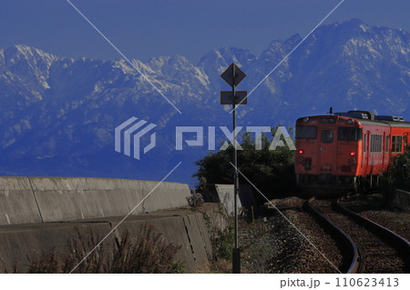 壁のようにそびえる立山連峰のもとのんびりと走る氷見線キハ40系気動車_2023/12/30撮影 壁のようにそびえる立山連峰のもとのんびりと走る氷見線キハ40系気動車_2023/12/30撮影 110623413