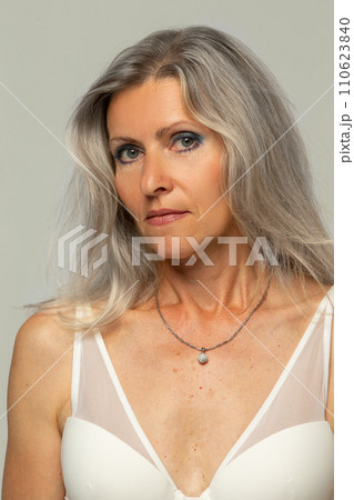 Beautiful grey-haired 50s woman looking at camera isolated on white.  110623840
