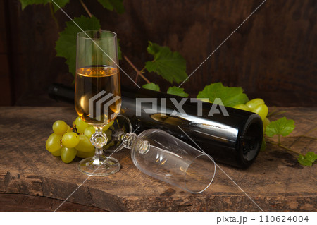Still life with glass of white wine and grapes on vintage wooden background.. Still life with glass of white wine and grapes on vintage wooden background.. 110624004