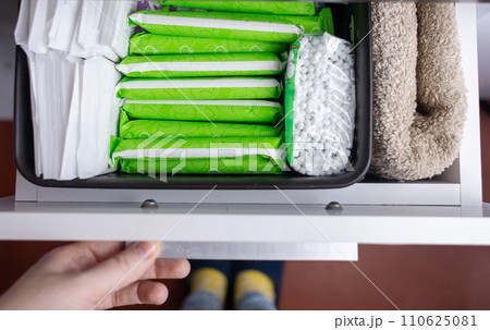 Sanitary napkin, tampon and cotton plant flower. Women hands pull out drawer containing hygiene products to help with menstruation. Cotton flower symbolizes absence of plastic. Made from eco materials Sanitary napkin, tampon and cotton plant flower. Women hands pull out drawer containing hygiene products to help with menstruation. Cotton flower symbolizes absence of plastic. Made from eco materials 110625081