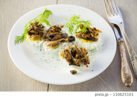 boiled eggs stuffed with mushrooms and spices in a plate . 110625101