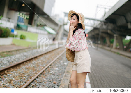 young asian woman traveler with weaving basket happy smiling looking to a camera beside train railway. Journey trip lifestyle, world travel explorer or Asia summer tourism concept. young asian woman traveler with weaving basket happy smiling looking to a camera beside train railway. Journey trip lifestyle, world travel explorer or Asia summer tourism concept. 110626060