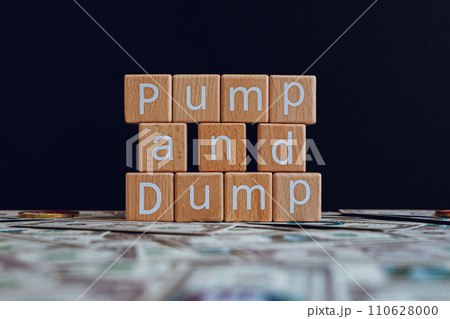 Wooden blocks with the text "Pump and Dump" on a black background and crypto banknotes scattered on the ground. 110628000