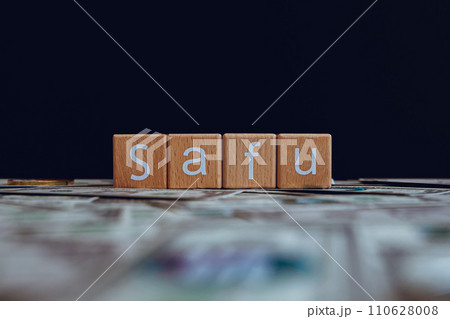 Wooden blocks with the text "Safu" on a black background and crypto banknotes scattered on the ground. Wooden blocks with the text "Safu" on a black background and crypto banknotes scattered on the ground. 110628008