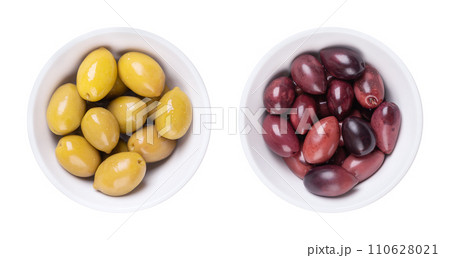 Green and Kalamata olives with pit, pickled whole, large Greek table olives, in white bowls. Green olives picked when still unripe, and Kalamata olives picked when ripe, both preserved in a brine. 110628021