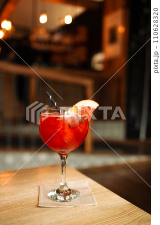 Orange cocktail with grapefruit, ice and rosemary in a transparent glass on a wooden table at style cafe 110628320