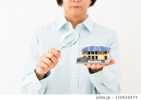 戸建ての住宅模型とルーペを持つミドル女性 110628474