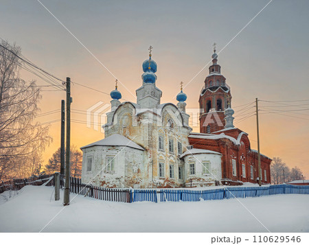 Resurrection Cathedral cherdyn. Ancient architecture is surrounded by tall white drifts and orange sunset skies. 110629546