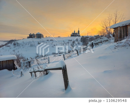 Ancient architecture is surrounded by tall white drifts and orange sunset skies. Ancient architecture is surrounded by tall white drifts and orange sunset skies. 110629548