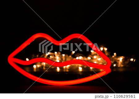 Blurry neon red lips close-up on a black isolated background. Blurry neon red lips close-up on a black isolated background. 110629561