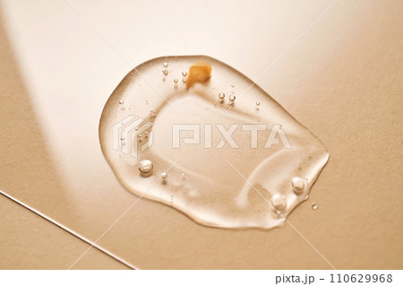 A drop of transparent cosmetic gel on a beige background. A drop of transparent cosmetic gel on a beige background. 110629968
