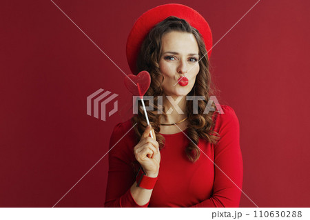 stylish woman against red background sending kiss 110630288