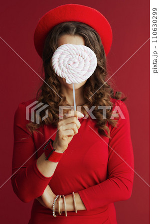elegant female in red dress and beret on red background 110630299