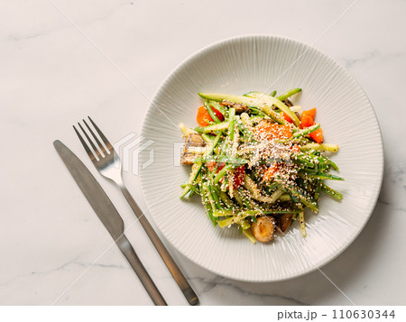 Delicious pork meat salad with cucumber in asian style with amaranth popcorn or popped amaranth (replaceable sesame) on white marble background. Topview, copyspace. Idea salad recipe healthy food menu Delicious pork meat salad with cucumber in asian style with amaranth popcorn or popped amaranth (replaceable sesame) on white marble background. Topview, copyspace. Idea salad recipe healthy food menu 110630344