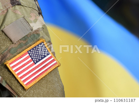 American Flag on Soldiers arm and flag of the Ukraine at background. US military support Ukraine. 110631187