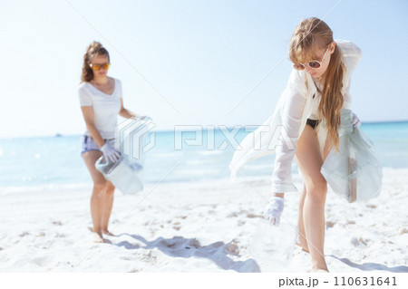 concerned female volunteers on ocean shore collecting trash concerned female volunteers on ocean shore collecting trash 110631641