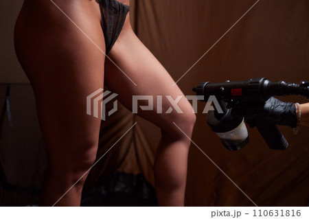 Cosmetologist using airbrush for spray tan apply to young woman body in beauty salon. 110631816