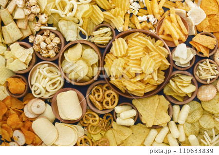 Colorful mix of salty snacks for beer varieties: chips and pretzels, onion rings and crackers. Non-healthy junk food background Colorful mix of salty snacks for beer varieties: chips and pretzels, onion rings and crackers. Non-healthy junk food background 110633839