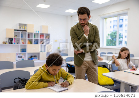 Man primary school teacher in classroom with pupils. 110634073