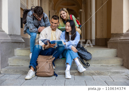 Students reading books studying or working on project while sitting on stairs of college campus. 110634374