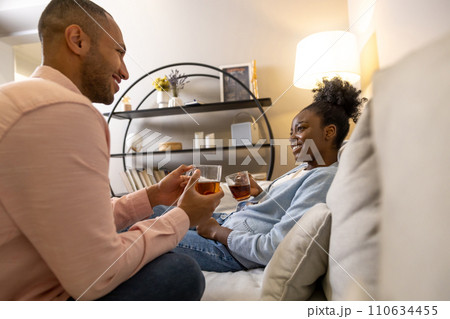 Man and woman enjoying hot tea and pleasant conversation while sitting together on couch Man and woman enjoying hot tea and pleasant conversation while sitting together on couch 110634455