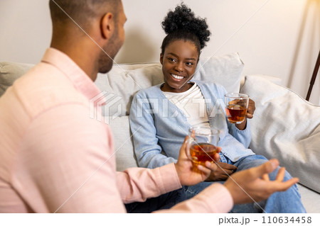 Man and woman enjoying hot tea and pleasant conversation while sitting together on couch Man and woman enjoying hot tea and pleasant conversation while sitting together on couch 110634458