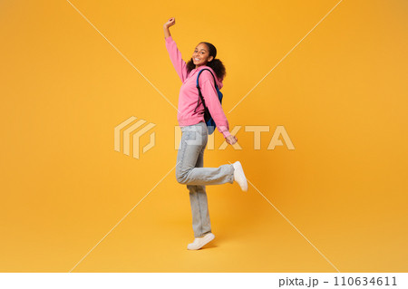 black student girl posing with blue backpack over yellow background black student girl posing with blue backpack over yellow background 110634611