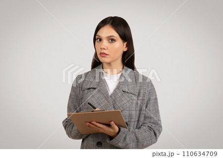 Focused woman with clipboard, serious about her work 110634709