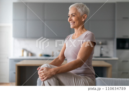 Cheerful Mature Woman Doing High Knees Exercise In Living Room Cheerful Mature Woman Doing High Knees Exercise In Living Room 110634789