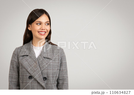Smiling woman in plaid jacket looking to the side at free space 110634827