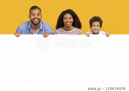 Offer for families. Black parents and son leaning on white advertisement board Offer for families. Black parents and son leaning on white advertisement board 110634836