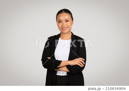Confident young Asian businesswoman with arms crossed wearing a black blazer 110634904