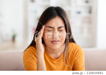 Closeup of unhealthy young asian woman touching her head Closeup of unhealthy young asian woman touching her head 110634981
