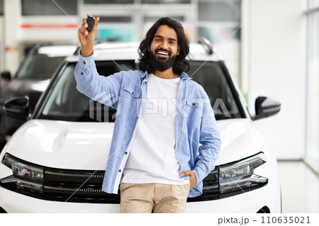 Emotional handsome eastern guy raising hand with car key 110635021