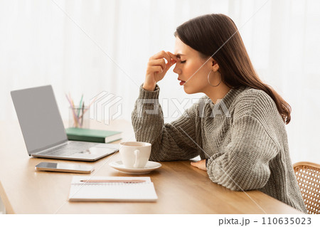 Exhausted young woman entrepreneur sitting at home office 110635023