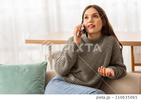 Cheerful pretty young woman have phone conversation at home 110635065