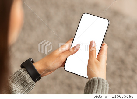 Unrecognizable young lady using smartphone with white screen 110635066