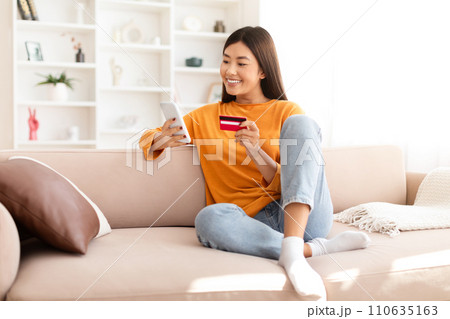 Cheerful chinese lady make online order while resting at home Cheerful chinese lady make online order while resting at home 110635163