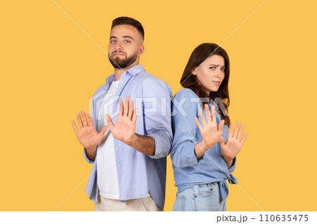 Couple gesturing stop with hands, standoffish poses, yellow background 110635475