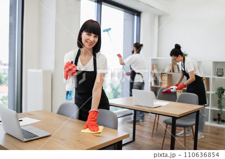 Caucasian young woman holding sponge and detergent cleaning on table in office. 110636854