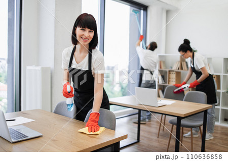 Caucasian young woman holding sponge and detergent cleaning on table in office. 110636858