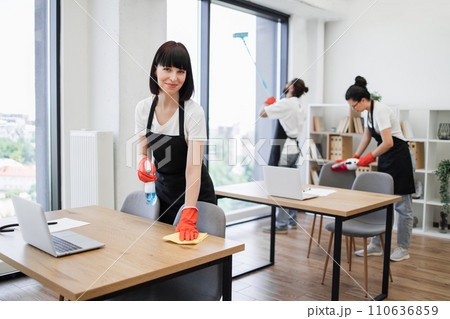 Caucasian young woman holding sponge and detergent cleaning on table in office. 110636859