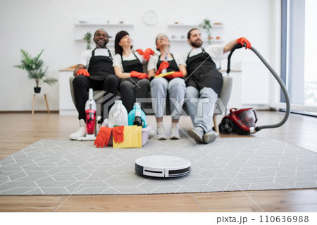 Focus on robot vacuum cleaner cleans floor while team of housekeepers resting. 110636988