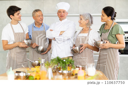 Group of cooks with utensils posing in kitchen Group of cooks with utensils posing in kitchen 110637750